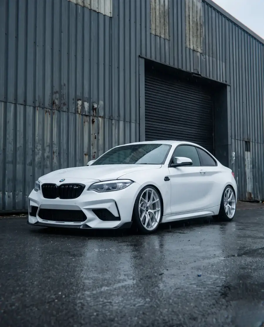 BMW M2 blanco con AXYS FAN Silver frente al galpon